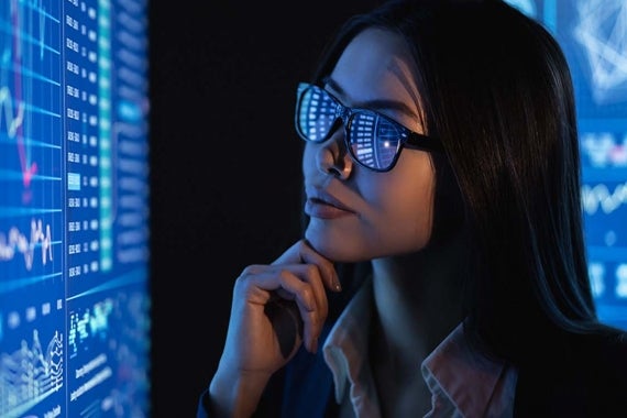 Woman wearing glasses analyzing data on a monitor